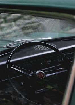 menu-04 Close-up of a classic car steering wheel showcasing vintage design and details.