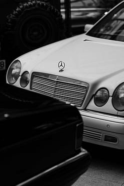 menu-05 Artistic black and white photo of a classic Mercedes Benz, showcasing elegant design and luxury.
