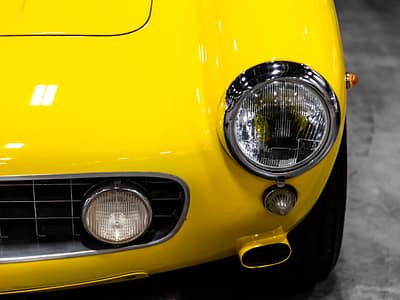 menu-17 Detailed view of a yellow vintage car's headlight showcasing classic automotive design.