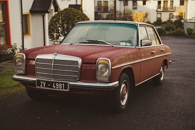 menu-18 Classic red Mercedes Benz parked on a wet street in Dublin, showcasing automotive heritage.