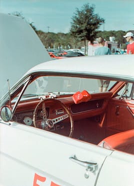 menu-13 Classic red and white vintage car interior with hanging dice on display in Orlando. Vibrant and nostalgic style.