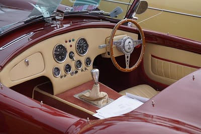 menu-09 Close-up of a vintage convertible's interior featuring a classic dashboard and wooden steering wheel.